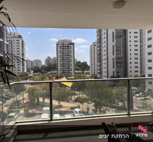 מרפסת עם רשת נגד יונים ונוף עירוני
